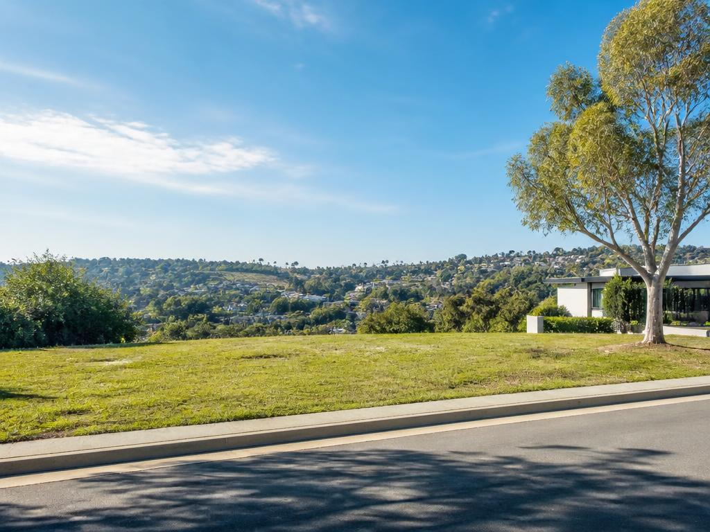 A grassy vacant building lot with hills in the distance